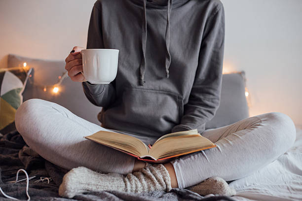 istock Girl drinking hot tea and reading book in bed 501912292