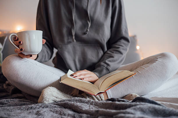 istock Girl drinking hot tea and reading book in bed 501912432