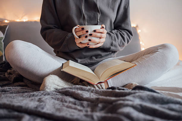 istock Girl drinking hot tea and reading book in bed 501912576