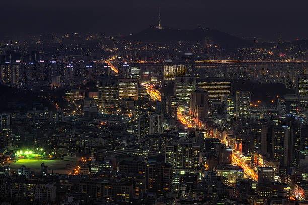 Gangnam and busy seocho district at night with the seoul n tower in the distance covered by the smog. traffic and city light illuminating the city.