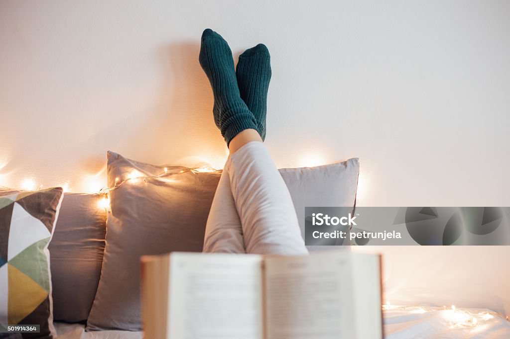 Women relaxing in bad and reading a book Young women relaxing in bad while reading book and enjoying in decorative light Reading Stock Photo