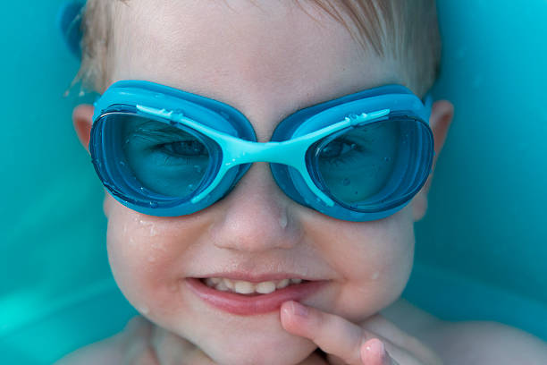 Portrait of happy little kid boy resting near the pool and having fun on family vacations in a hotel resort. Healthy child playing in water, swimming and splashing