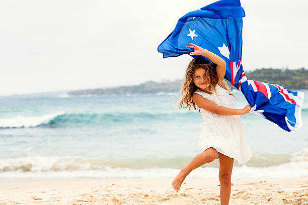 escuela preescolar chica con bandera australiana en la playa - australia australia day celebration flag fotografías e imágenes de stock