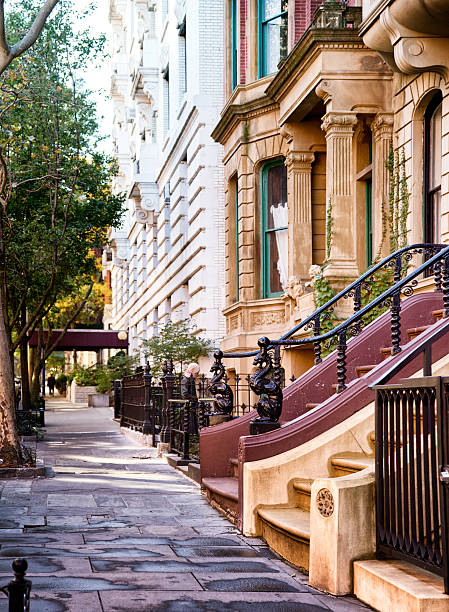Upper west side sidewalk with luxury residential building facades and stairs.