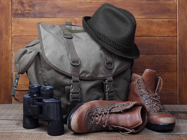 istock Rucksack with old boots, binocular and hat on wooden background 501935494