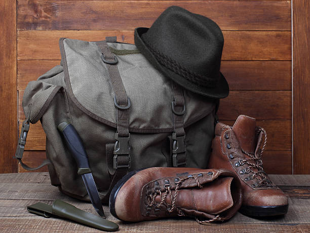 istock Rucksack with old boots, knife and hat on wooden background 501935926