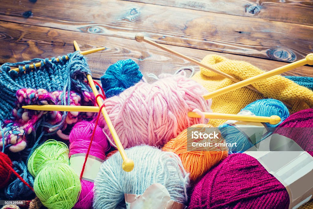 handcraft view from above on a wooden table with lots of balls of wool and knitting needles. Place for text Knitting Stock Photo