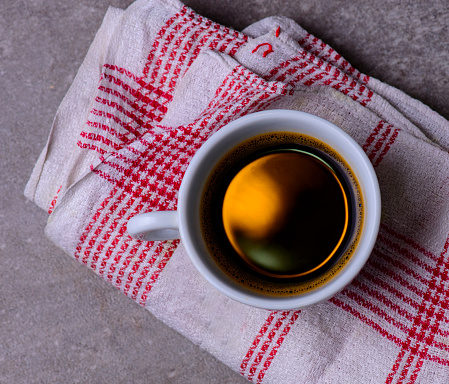 cup of black coffee on a white red table cloth, from above