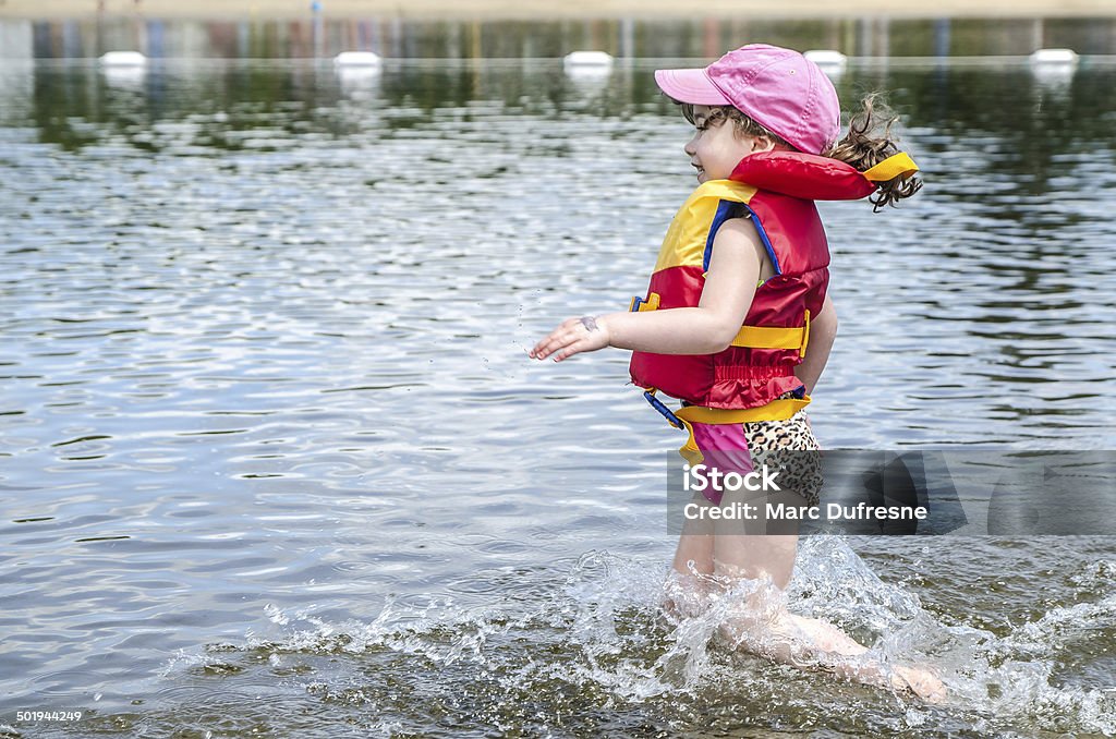 Running in water A little girl wearing a life jacket runs into the water of a lake during summer 4-5 Years Stock Photo