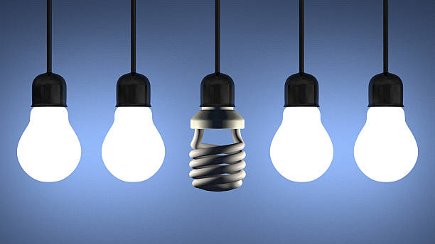 istock Dead spiral lightbulb hanging among glowing tungsten ones on blue 501945647
