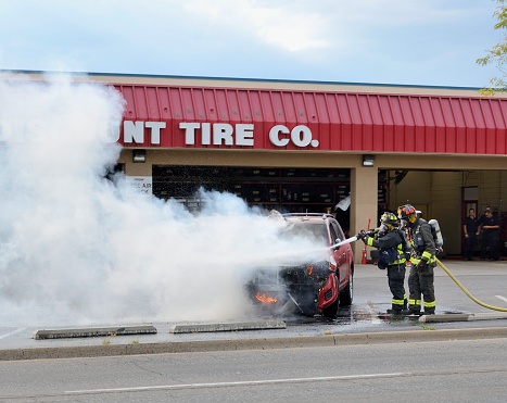 Fort Collins, Colorado, USA - September 24, 2012: Firefighters fighting the flames of a car fire at a Discount Tire Co. location as others look on.