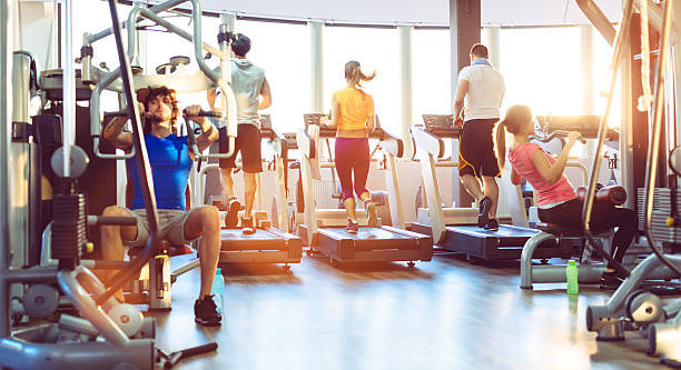 Group Of People Exercise in a gym. Group of young people, friends, exercise in a gym. Selective focus on people on treadmill. health club stock pictures, royalty-free photos & images