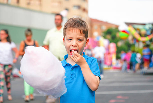 istock Cute kid eating cotton candy over fair background 501959541