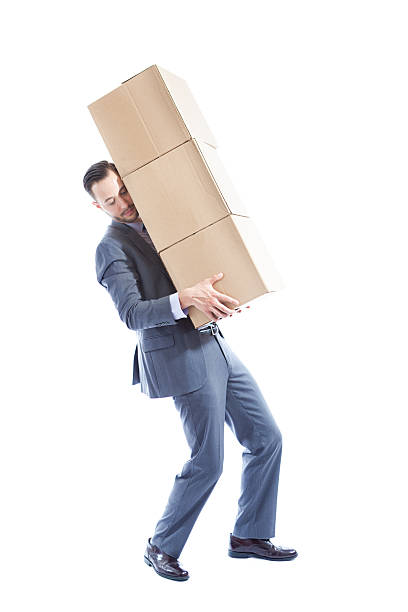 Businessman Moving a Stack of Heavy Boxes on White Background A businessman moving a large heavy stack of boxes. Isolated on white background. big cardboard box stock pictures, royalty-free photos & images