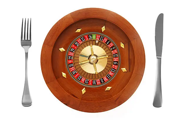 Roulette Wheel with a knife and fork on a white background.  Top View of a place setting isolated on white.