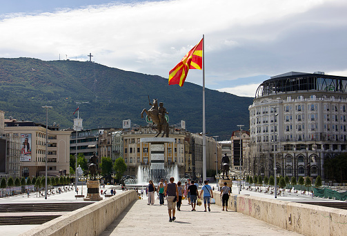 Skopje, Republic of Macedonia - September 6, 2015: People on stone bridge and the view of bronze statue of Alexander the Great on a rearing horse holding a sword high up in Skopje city main square, Former Yugoslav Republic of Macedonia (Macedonia FYR). Monument of Alexander the Great in Skopje central square, Republic of Macedonia. Giant bronze statue of Alexander the Great is 12 meters high. The official name is \