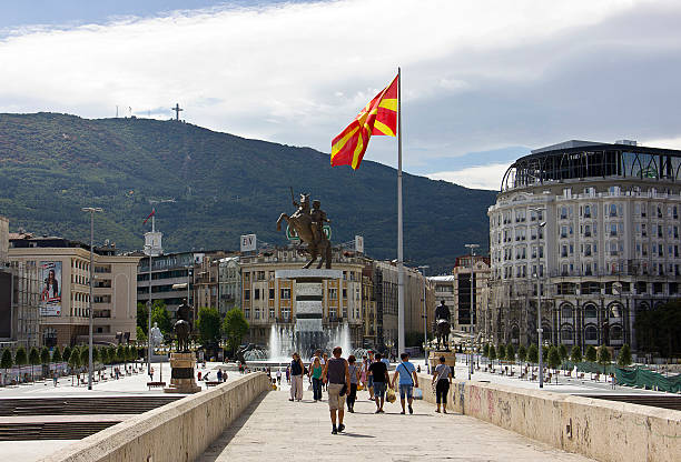 People on Skopje Square Skopje, Republic of Macedonia - September 6, 2015: People on stone bridge and the view of bronze statue of Alexander the Great on a rearing horse holding a sword high up in Skopje city main square, Former Yugoslav Republic of Macedonia (Macedonia FYR). Monument of Alexander the Great in Skopje central square, Republic of Macedonia. Giant bronze statue of Alexander the Great is 12 meters high. The official name is "A warrior on a horse" People are watching the statues. The statue, designed by sculptor Valentina Stevkovska. north macedonia stock pictures, royalty-free photos & images