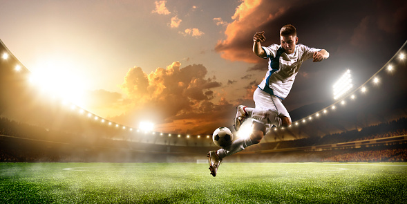 Soccer player in action on sunset stadium background