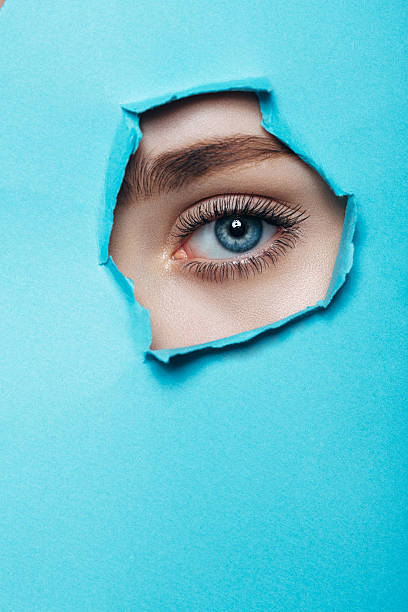 Girl watches through a hole in cardboard