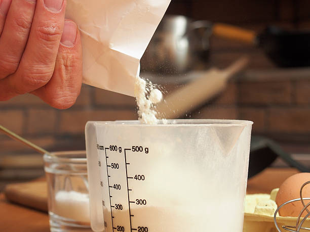 Pouring flour into measuring cup. Making yeast pancakes (crepes)
