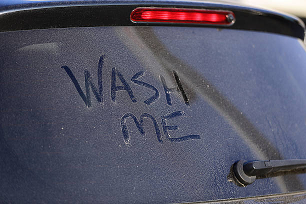 Dirty car window and wash me sign