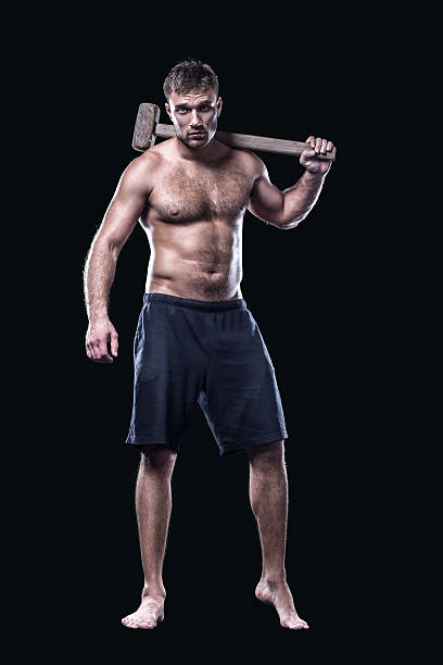 istock Sportsman with a sledgehammer next to tire isolated on black 501970710
