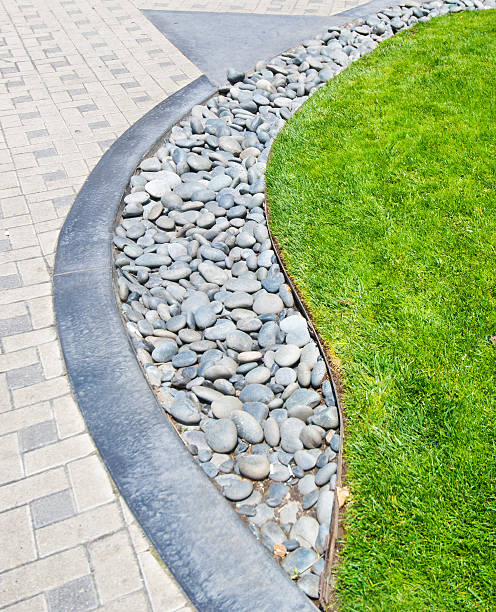istock River rock stone border against fresh grass and paving bricks 501973560
