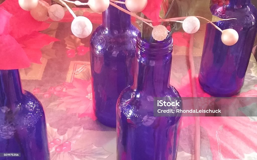 Blue Bottles Close up of 4 blue bottles with Holiday poinsettias and silver balls. 2015 Stock Photo