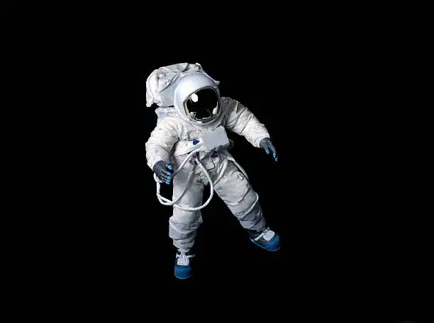 Astronaut wearing a plain pressure suit without symbols or insignia against a black background.