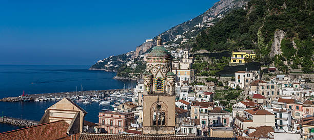 Close view to Duomo di Amalfi bell tower and town harbor at the background. Amalfi.
