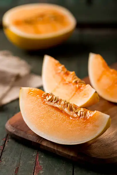 sliced ripe melon on a cutting board on rustic wooden background