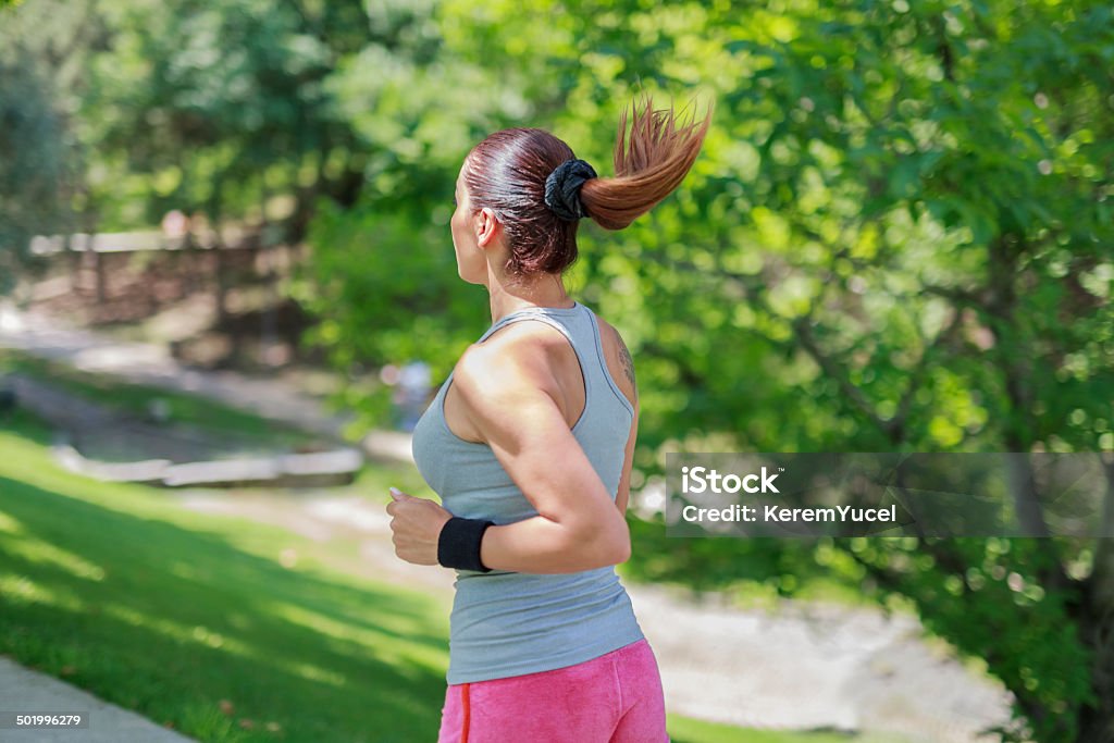 beautiful young woman running in park pathway Young female running in the park. There is a shallow depth of field. Active Lifestyle Stock Photo