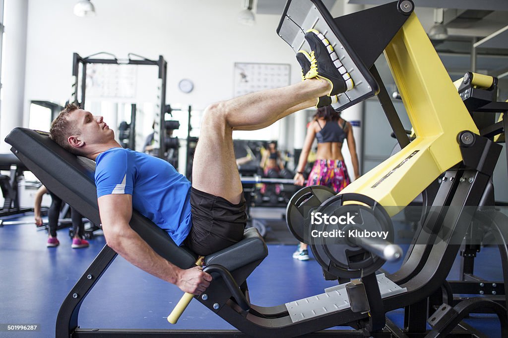 Young people in gym - leg press workout Young man exercising in gym, using leg press machine. Leg Press Stock Photo