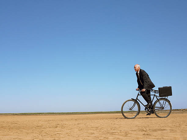 istock Businessman Riding Bicycle In Desert 501996701
