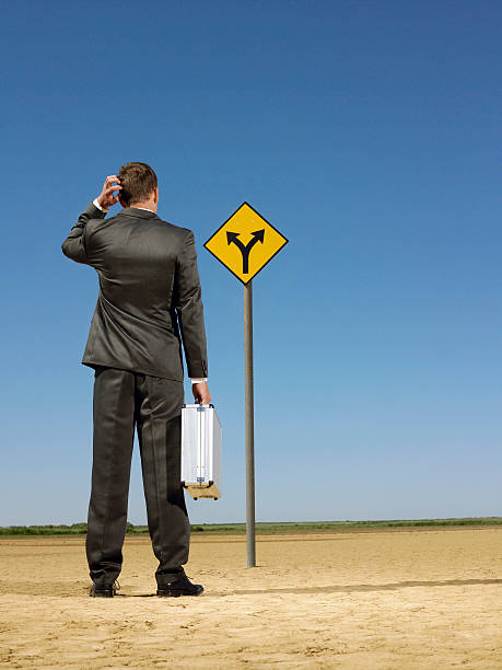 istock Businessman Looking At Road Sign On Desert 501996707