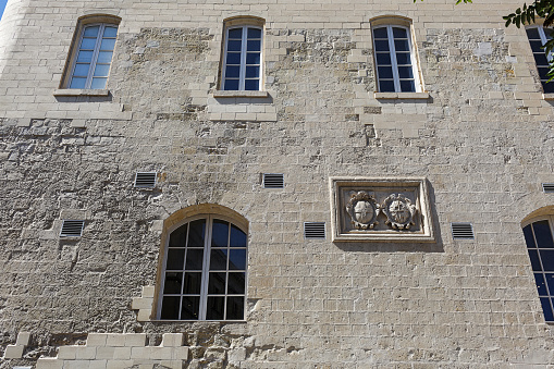 Old stone building facade in Malta with arched windows, ornamental stone carving and a rough weathered surface texture
