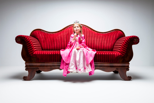 6 year princess girl sitting on red vintage sofa.