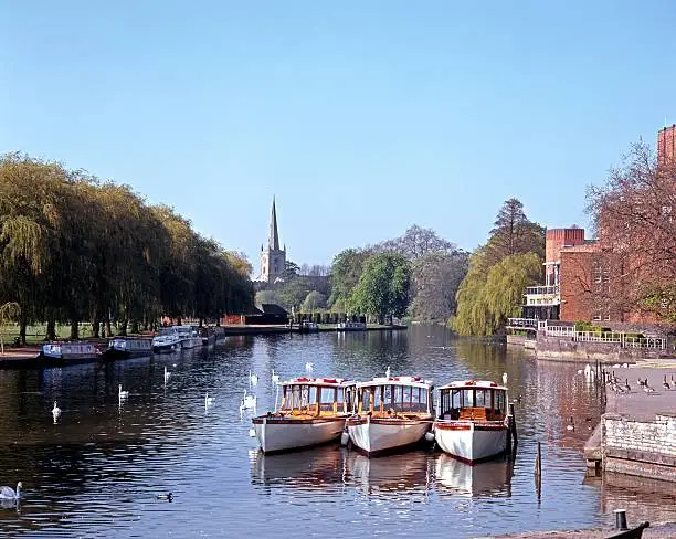River Avon with pleasure boats moored and Church to rear, Stratford-upon-Avon, Warwickshire, England, UK, Western Europe.