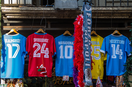 Naples, Italy - December 12, 2015: A shop of not original Naples soccer team T-shirt of the recent players Hamsik, Insigne, Reina, Mertens and most famous old player Diego Armando Maradona.