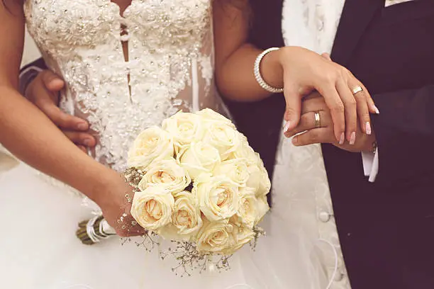 Photo of Detail of bride's roses bouquet and hands holding