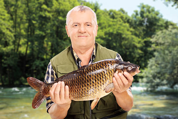 istock Mature fisherman showing his catch standing by a river 502019313