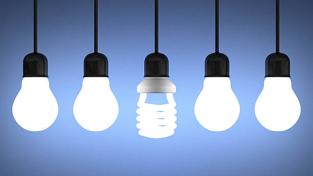 istock Glowing spiral light bulb hanging among tungsten ones on blue 502019959