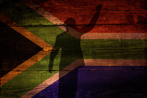 An South African flag on a grunge wooden background with a shadow overly for freedom.