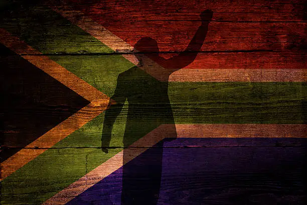 An South African flag on a grunge wooden background with a shadow overly for freedom.