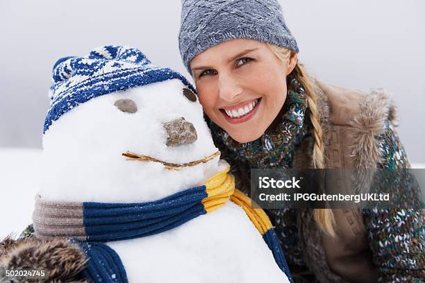 Cheerful Young Woman By Snowman Stock Photo - Download Image Now - Adult, Adults Only, Beautiful People