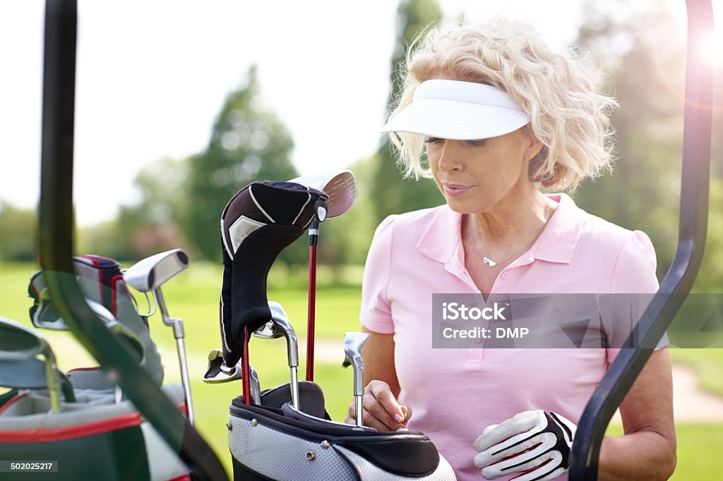 Mature female golfer choosing a right club Mature female golfer choosing a golf club for her next shot. 50-59 Years Stock Photo