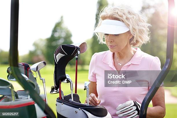 Mature Female Golfer Choosing A Right Club Stock Photo - Download Image Now - 50-59 Years, Adult, Adults Only