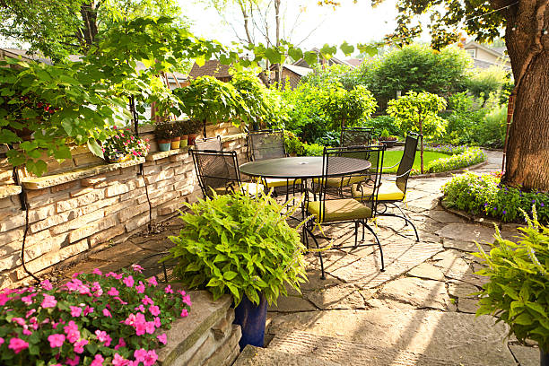 exuberante jardín del patio con jardín de plantas, muebles rellenos, flores - chair grass flower bed nobody fotografías e imágenes de stock