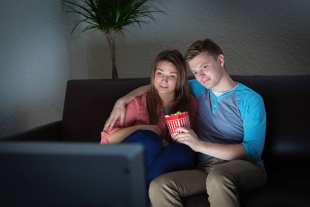 jovem casal assistindo tv juntos em casa - entertainment center watching tv television popcorn - fotografias e filmes do acervo
