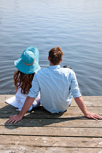 istock couple sitting on pier at waterfront 502035539